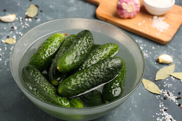 Bowl with fresh cucumbers for preservation on green background