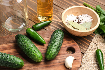 Fresh cucumbers and ingredients for preservation on wooden background