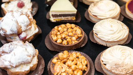 fresh cakes on a bakery showcase close-up. concept of coffee break, wrong eating habits, empty calories, shop window decoration