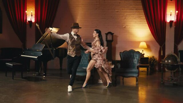 Passionate asian woman confidently walking to her dance partner. Male dancer support woman while she performing low back bend down with straightening one leg up. Elegant couple holding hands in dance