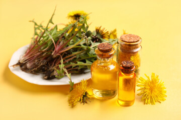 Bottles with cosmetic oil and plate of dandelion flowers on yellow background