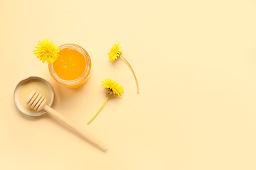 Jar with dandelion honey on beige background