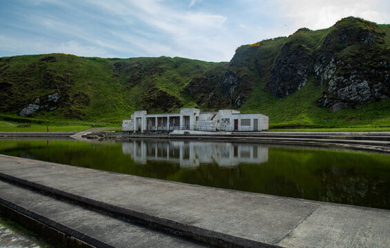 Old Royal Tarlair Lido, outdoor sea swimming pool. Old Victorian building in ruins with beautiful reflection in the water of the old swimming pool in MacDuff, near Banff on the east coast of Scotland