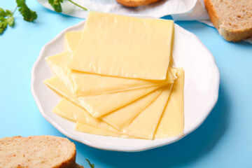 Plate of tasty processed cheese with bread on blue background