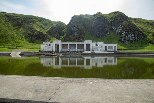 Old Royal Tarlair Lido, outdoor sea swimming pool. Old Victorian building in ruins with beautiful reflection in the water of the old swimming pool in MacDuff, near Banff on the east coast of Scotland