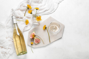 Board with bottle and glass of dandelion wine on white background