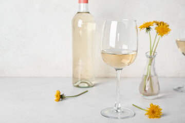 Bottle and glasses of dandelion wine on white table