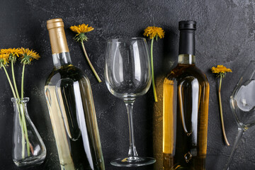 Bottles and glasses of dandelion wine on black background