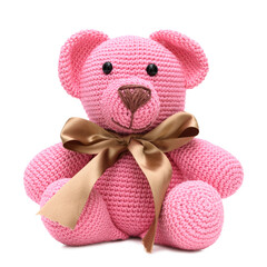 Urso rosa em pelúcia com uma fita marrom no pescoço,  feito na técnica de crochê amigurumi,...