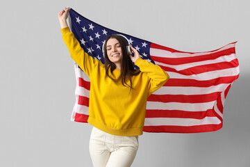 Young woman with USA flag on light background