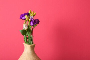 Vase with eustoma flowers on red background