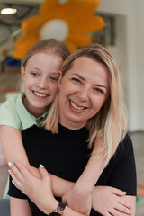 A cute little girl kisses and hugs her mother in preschool