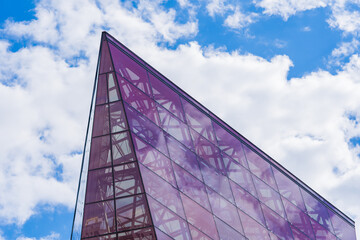 Stylish Glass Facade of Violet Semi-Transparent Glass Building Against Blue Sky with Sunbeams.