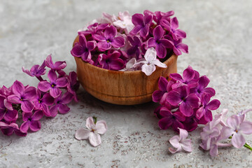 Obraz na płótnie Canvas Wooden bowl of beautiful fragrant lilac flowers on grunge grey background