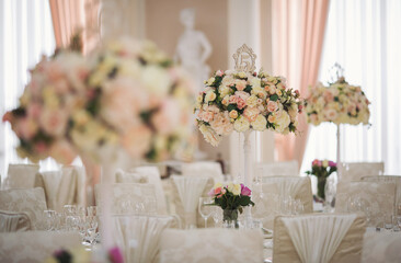 Banquet. Wedding table for guests, served with cutlery, flowers and covered with a tablecloth. Stylish wedding decor for a classic wedding in pastel shades. Beautiful flowers on table in wedding day.