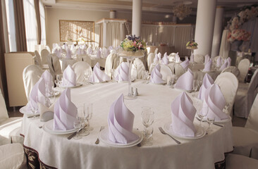 Wedding. Banquet. The chairs and round table for guests, served with cutlery, flowers and crockery and covered with a tablecloth. Stylish wedding decor for a classic wedding in pastel shades.