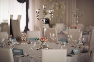 Wedding. Banquet. The chairs and round table for guests, served with cutlery, flowers and crockery and covered with a tablecloth. Stylish wedding decor for a classic wedding in pastel shades.