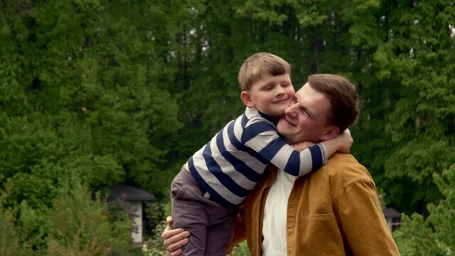 little boy hugging his uncle in front of the trees in summer, Wroclaw, Poland