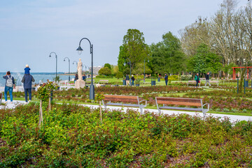 A green main square on the shore of Lake Balaton with trees, benches and flowers.