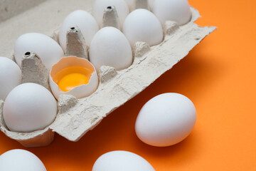 Ten white eggs in a carton package. Cardboard egg box on orange background