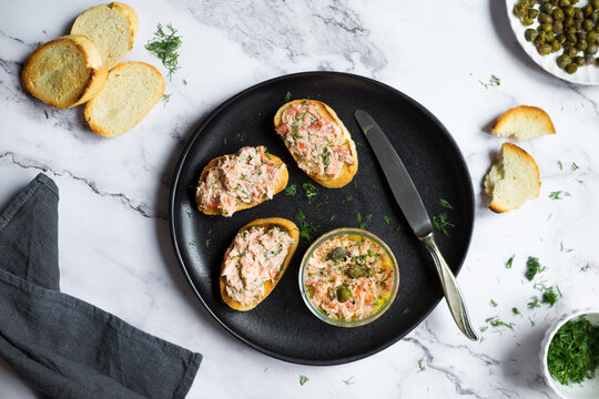 Salmon rillettes, mousse, pate and toasts on wooden background