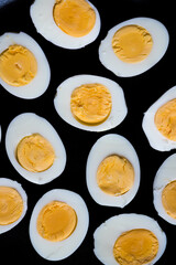 Boiled eggs pattern on a black background viewed from above. Top view. Egg half. Yolk.