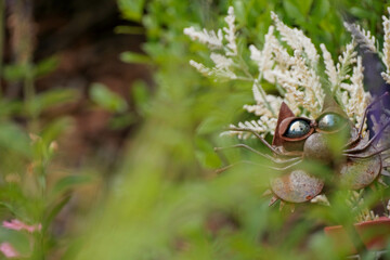 Cute cat sculpture hids behind plants in garden