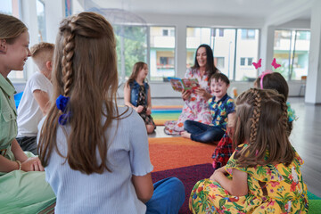 Reading time in an elementary school or kindergarten, a teacher reading a book to children in an elementary school or kindergarten. The concept of pre-school education. Selective focus