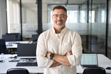 Handsome hispanic senior business man with crossed arms smiling at camera. Indian or latin...