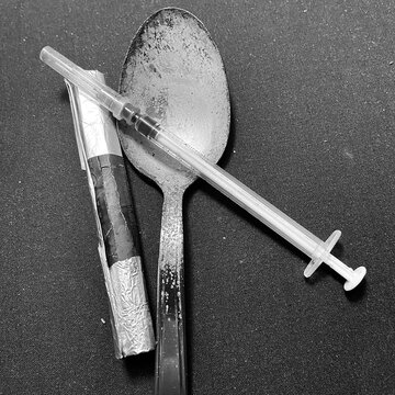 Tools for heroin and drug use. Spoon, syringe and blowtorch for smoking narcotic substances. Items for cocaine consumption. Image with neutral background.