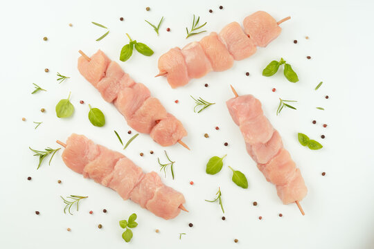 Chicken skewers.Chicken breast Fillets.Raw chicken.Ogranic food,healthy eating.Skewers from raw chicken meat fillet on a white plate for supermarket on white background.Food for retail.