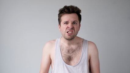European young man behaves aggressively, contorts an angry face, and threatens someone