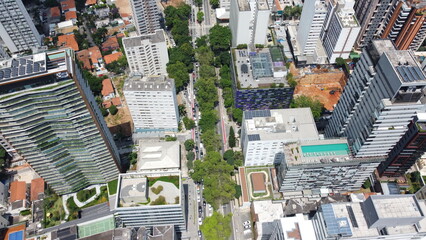 Visão aérea da cidade de São Paulo captada do alto por um drone entre os prédios e área verde...