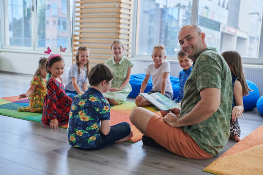 Reading time in an elementary school or kindergarten, a teacher reading a book to children in an elementary school or kindergarten. The concept of pre-school education. Selective focus