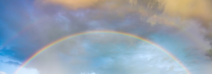 Natural background: dramatic sky and rainbow at sunset