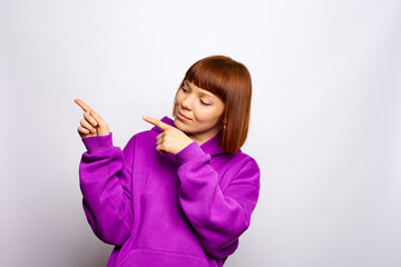 Woman in a purple hoody is showing aside. Isolated