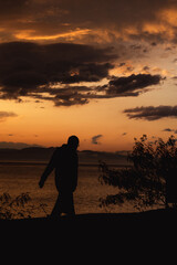 Obraz premium Man walking at sunset at bay.