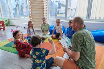 Reading time in an elementary school or kindergarten, a teacher reading a book to children in an elementary school or kindergarten. The concept of pre-school education. Selective focus