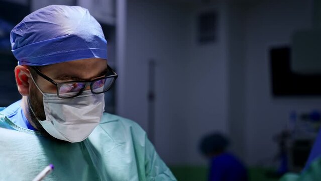 Chubby bearded Caucasian surgeon performing operation. Doctor uses special pen to mark the operated area on foot.