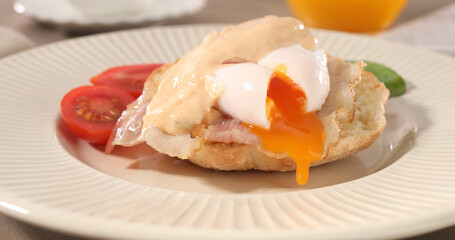 cut poached egg with bacon on a plate. boiled egg on bread with sauce. delicious breakfast with vegetables. serving food on a sunny day.