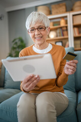 Senior woman caucasian female hold credit card online shopping at home