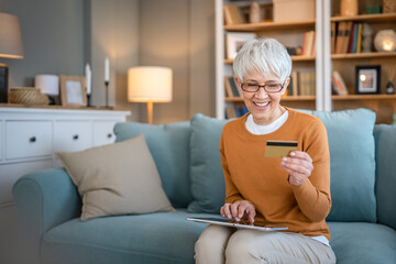 Senior woman caucasian female hold credit card online shopping at home