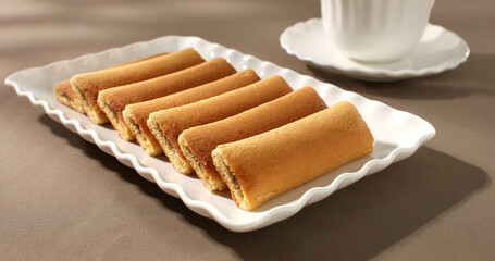 cookies with a cup of coffee on the table. strudel with fruit filling on a white plate. pastries on a brown background. sweet treat on a sunny day.