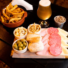 food plate with chips salami and cheese with glasses of beer