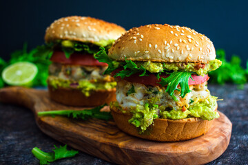 Shrimp Burgers with Cilantro and Guacamole on Sesame Seed Buns: Seafood hamburger sandwiches made topped with guacamole and sliced tomato