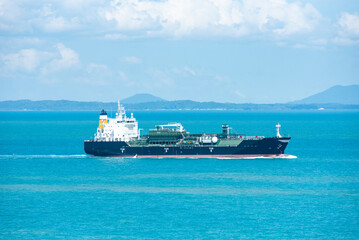 Cargo ship, gas tanker, sailing through peaceful, calm, blue sea on her voyage through the Singapore Strait. 