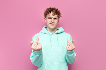 rude guy in mint hoodie showing middle finger on pink isolated background, furious man showing fuck...