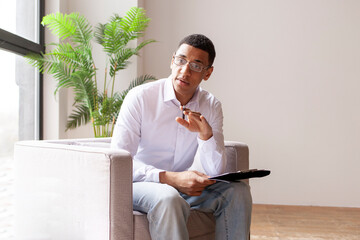 male african american psychologist in armchair consults and tells, session with psychotherapist, psychologist calms down - obrazy, fototapety, plakaty