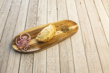 A delicious unit of empanada stuffed with chicken with red onion