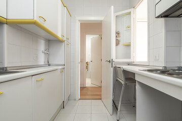 A small kitchen with white furniture with a worktop of the same color and yellow details